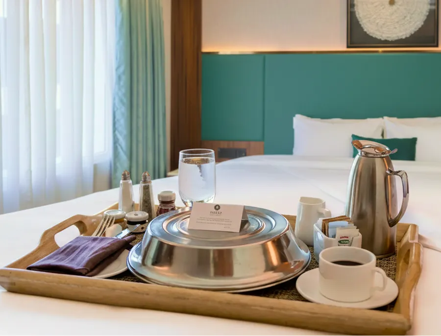 In-room dining tray with covered dishes on a guest room table
