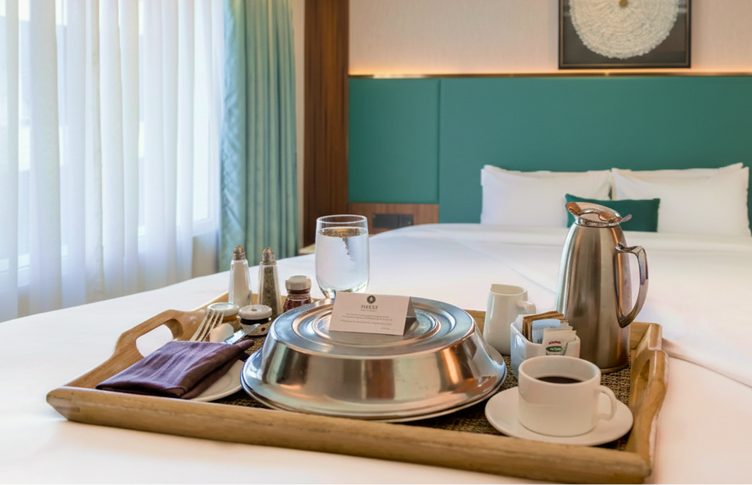 In-room dining tray with covered dishes on a guest room table